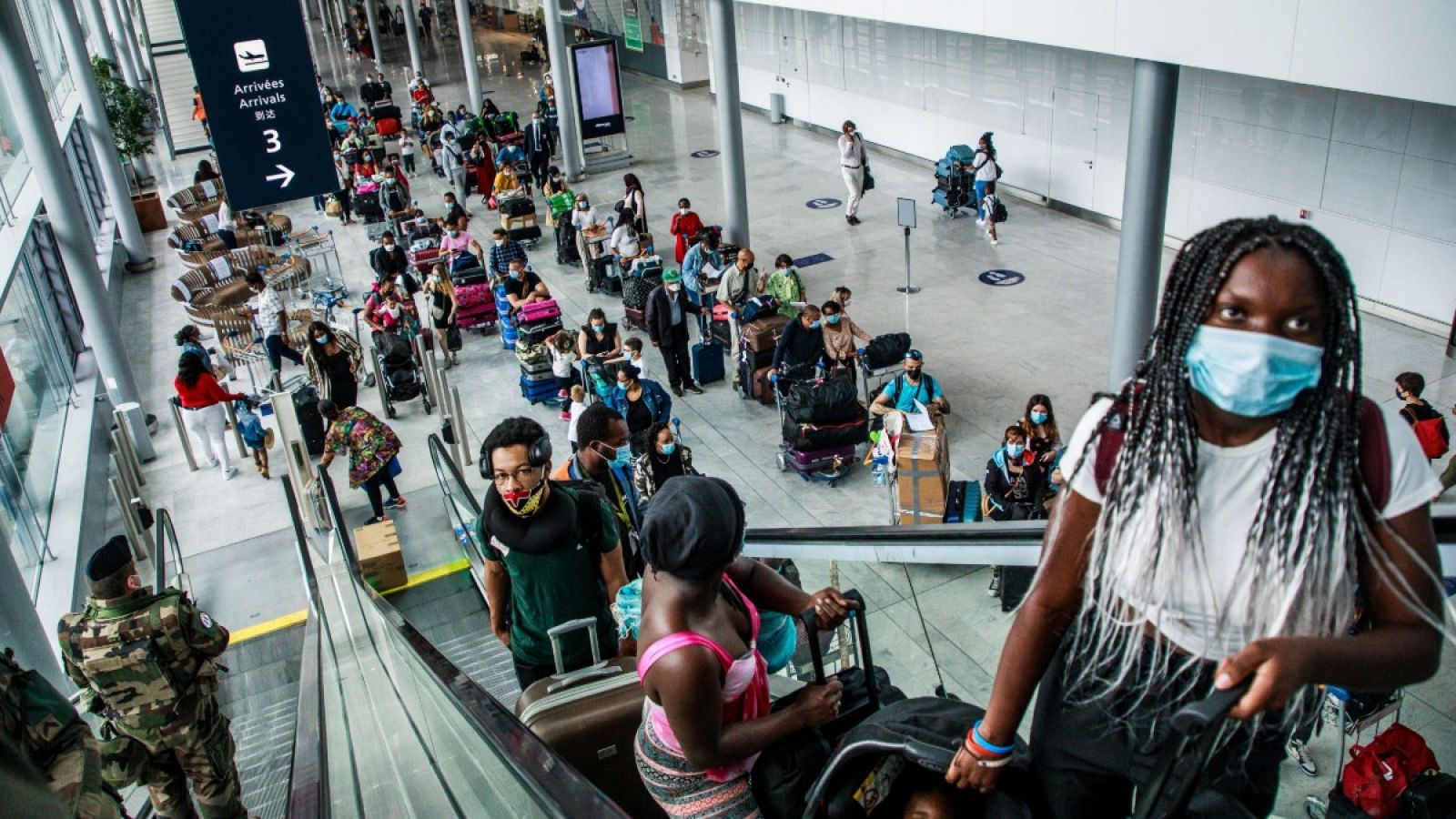 Pasajeros ataviados con mascarillas suben por una escalera mecánica en el Aeropuerto de Orly, cerca de París (Francia)