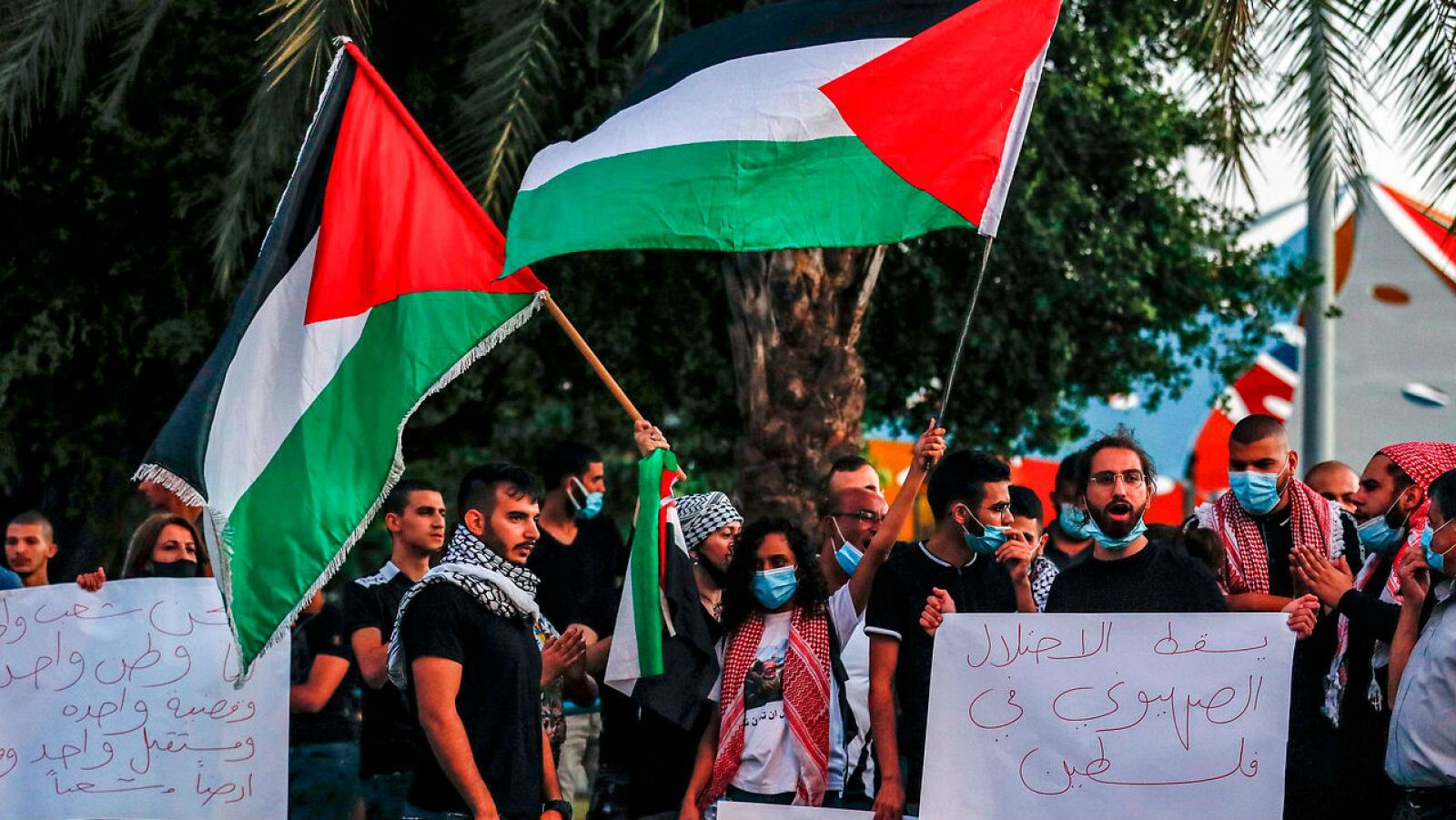 Los manifestantes, vestidos con máscaras debido a la pandemia del coronavirus COVID-19, ondean banderas palestinas mientras se reúnen para protestar contra los planes de Israel de anexionarse partes de Cisjordania