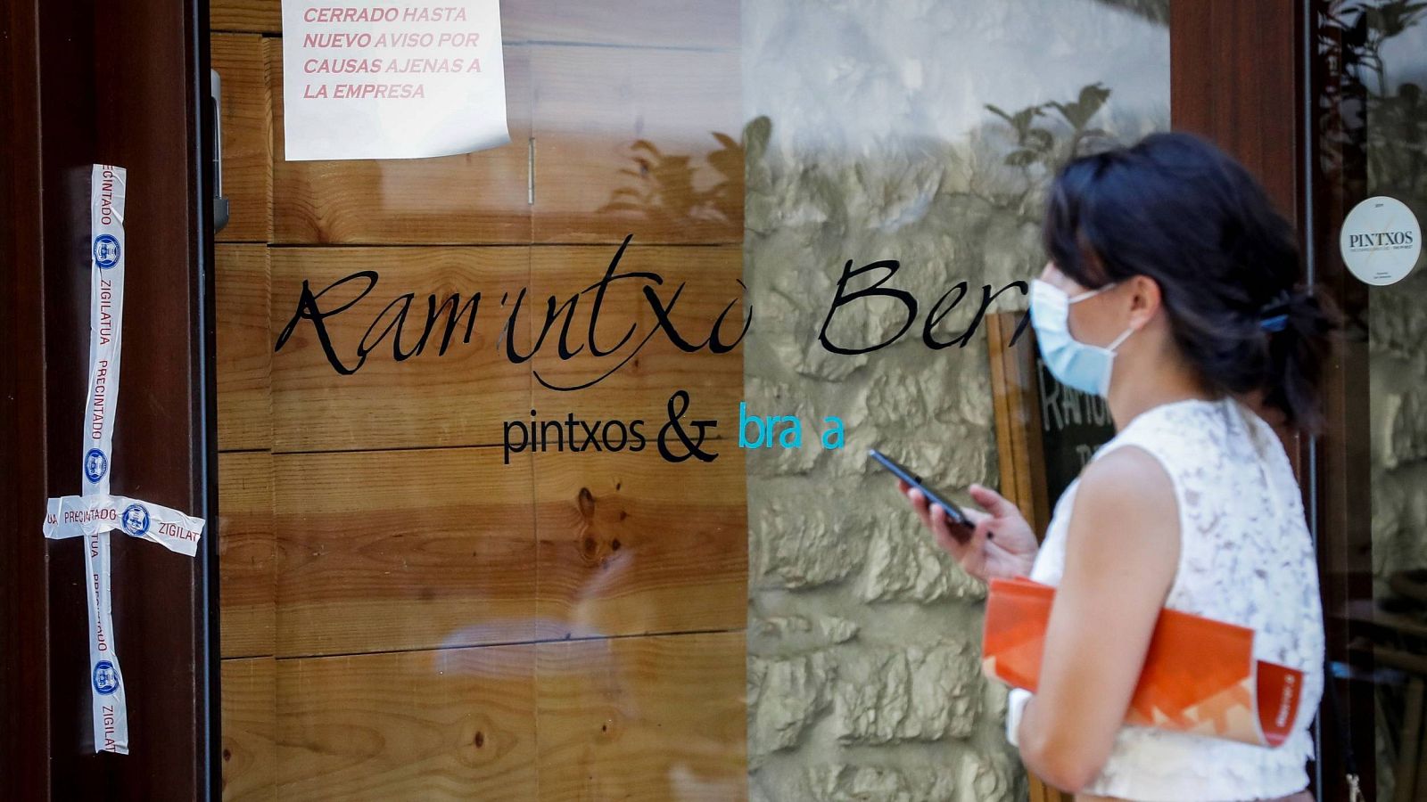 Una mujer pasa ante un bar precintado en San Sebastián para investigar un posible foco de coronavirus