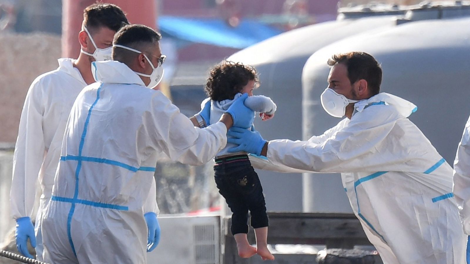 Funcionarios del departamento de inmigración ayudan a un niño a desembarcar de una patera