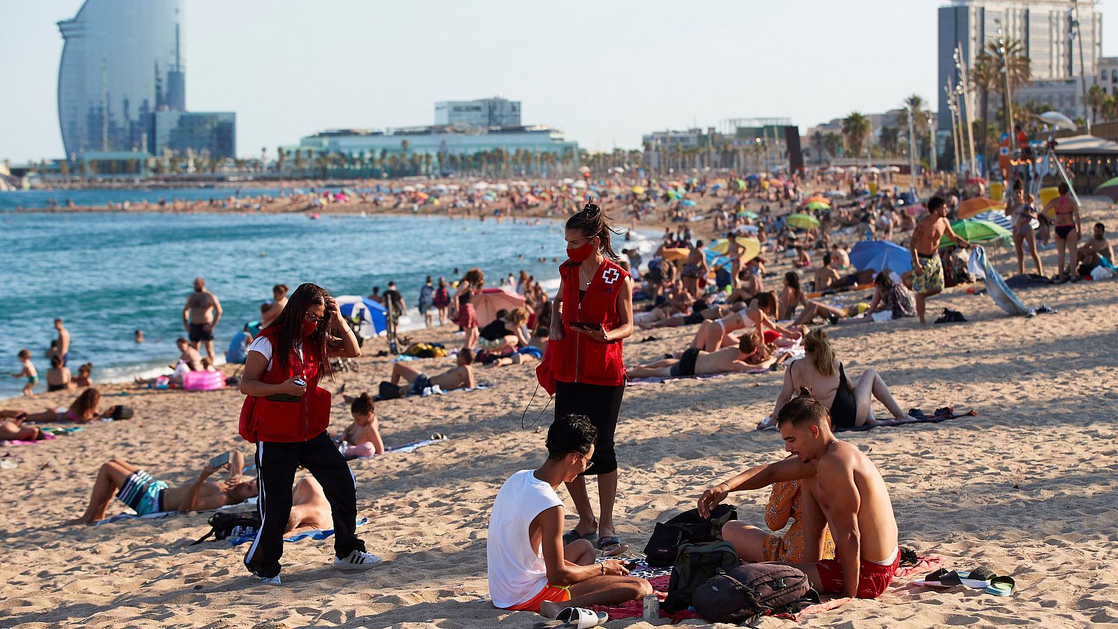 Miembros de Cruz Roja, durante una campaña de concienciación de contagios, en la playa de la Barceloneta.