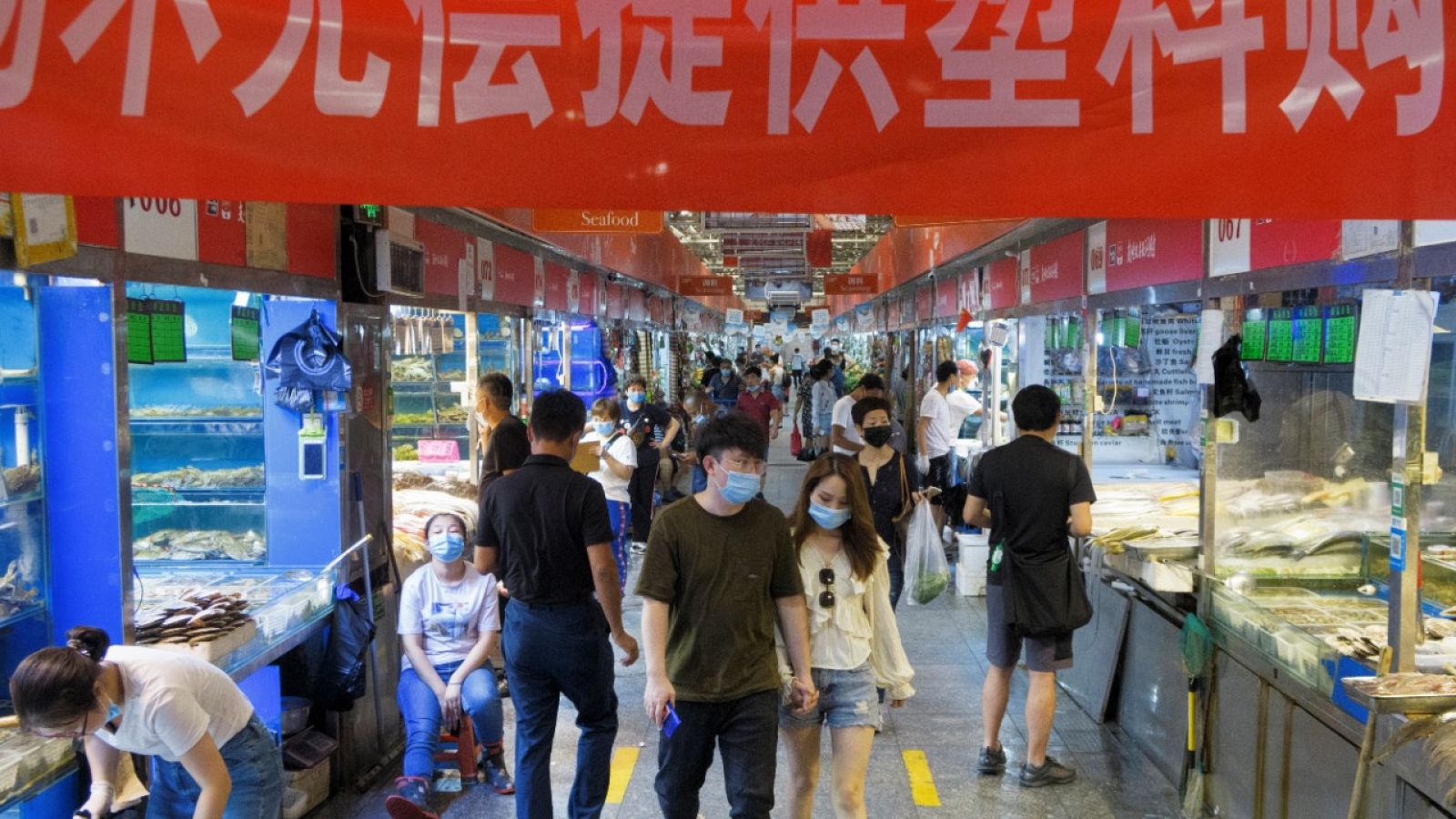 Gente caminando por un mercado de pescado, carne, fruta y vegetales en Pekín.