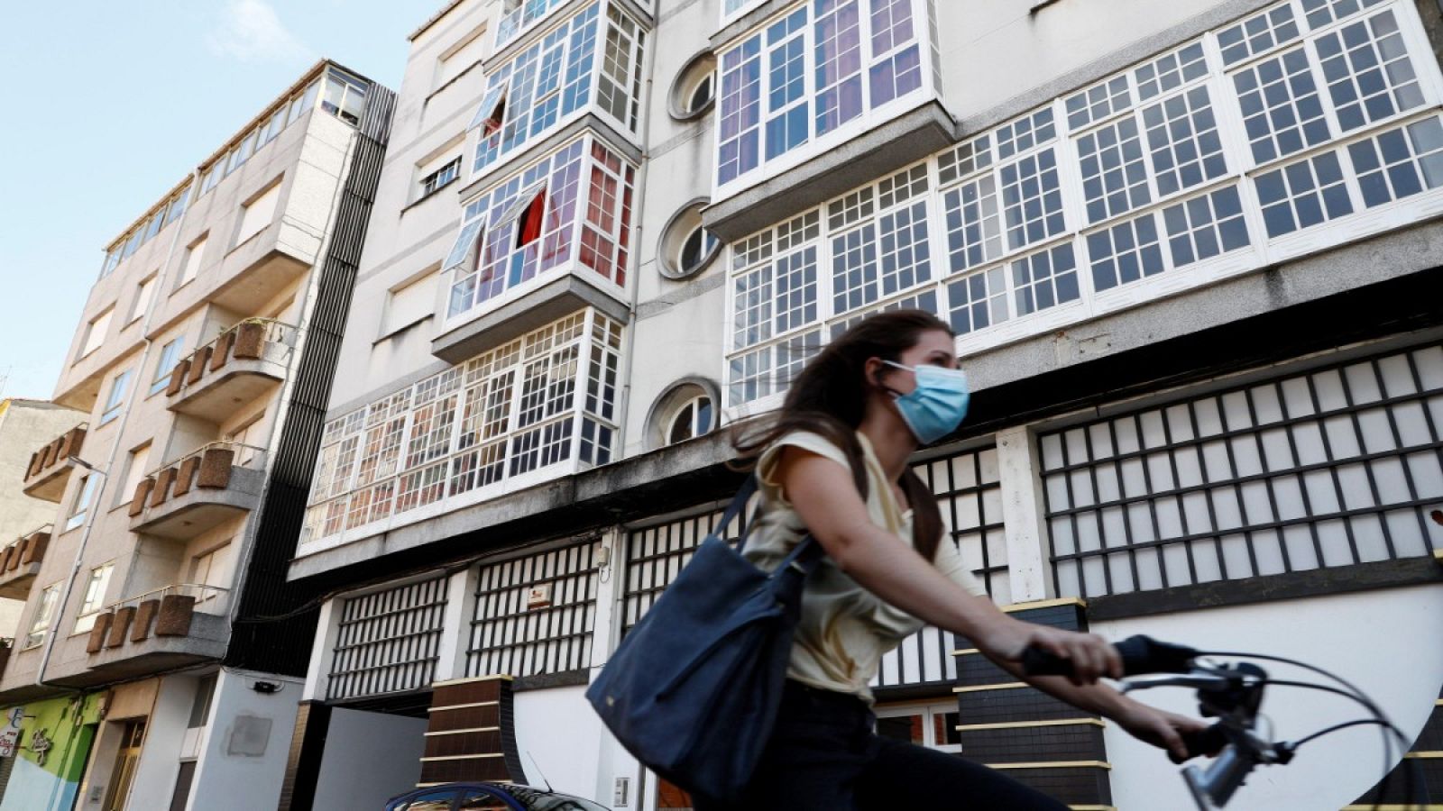 Una mujer monta en bicicleta junto a un edificio confinado en la localidad lucense de Monforte de Lemos