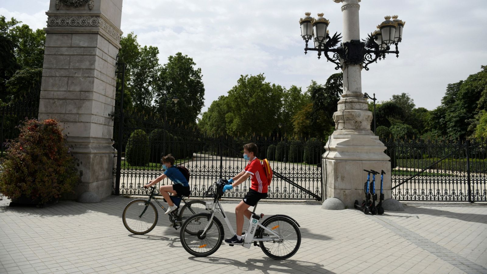 Dos jóvenes montan en bici en el exterior del parque del Retiro en Madrid
