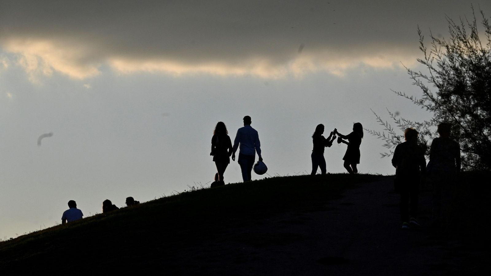 Personas viendo el atardecer desde el Parque del Cerro del Tío Pío, en el distrito de Puente de Vallecas, Madrid.