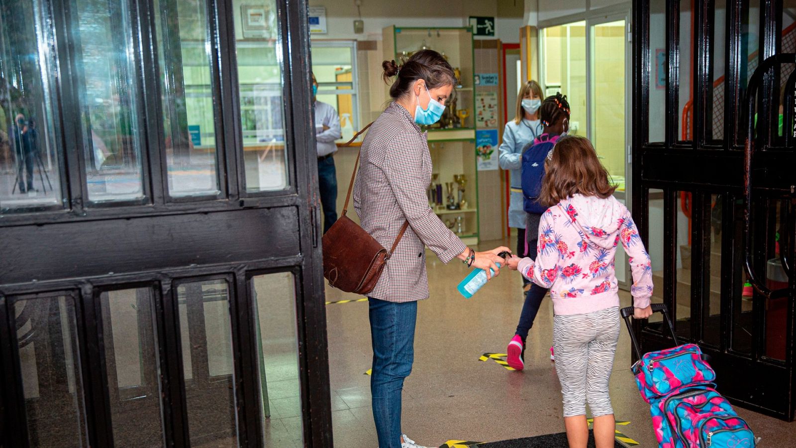 Una trabajadora de un colegio reparte gel hidroalcohólico entre los alumnos