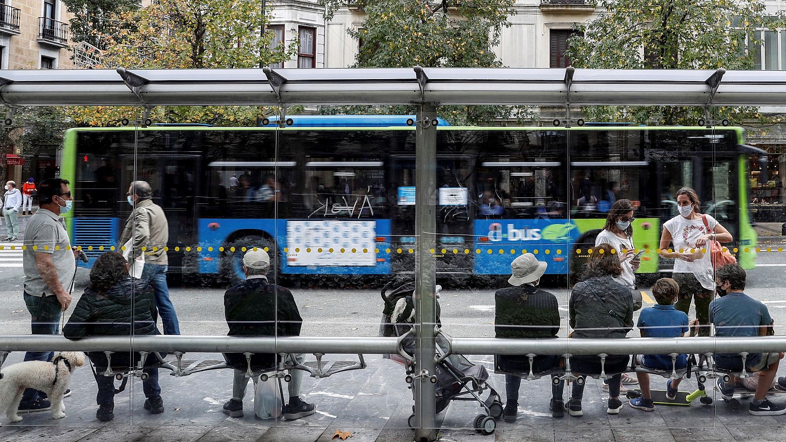 Un grupo de personas espera en una parada de autobús de San Sebastián.
