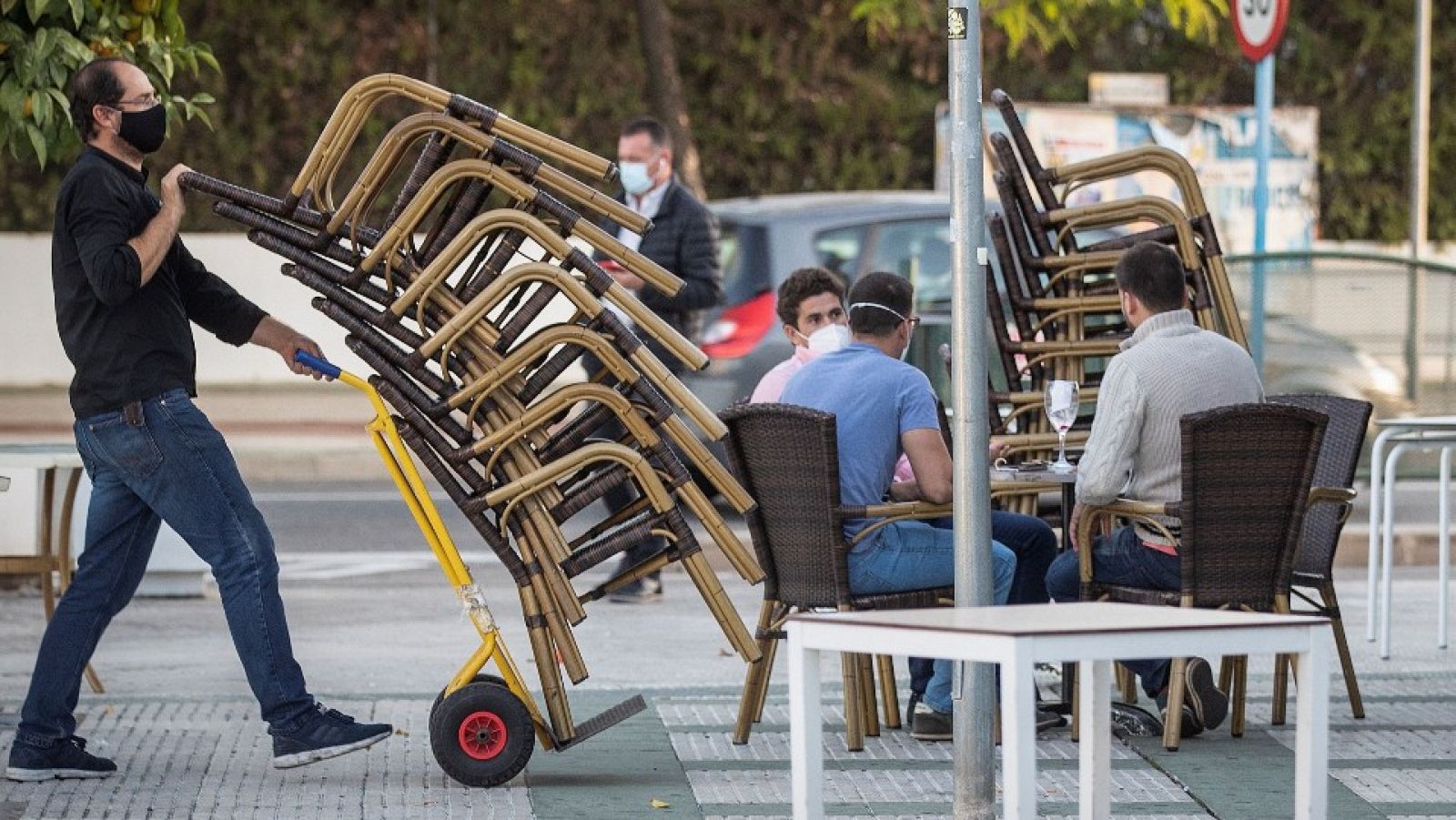 Camareros de un bar de Mairena del Aljarafe (Sevilla) recogen el mobiliario para proceder al cierre antes de las seis de la tarde