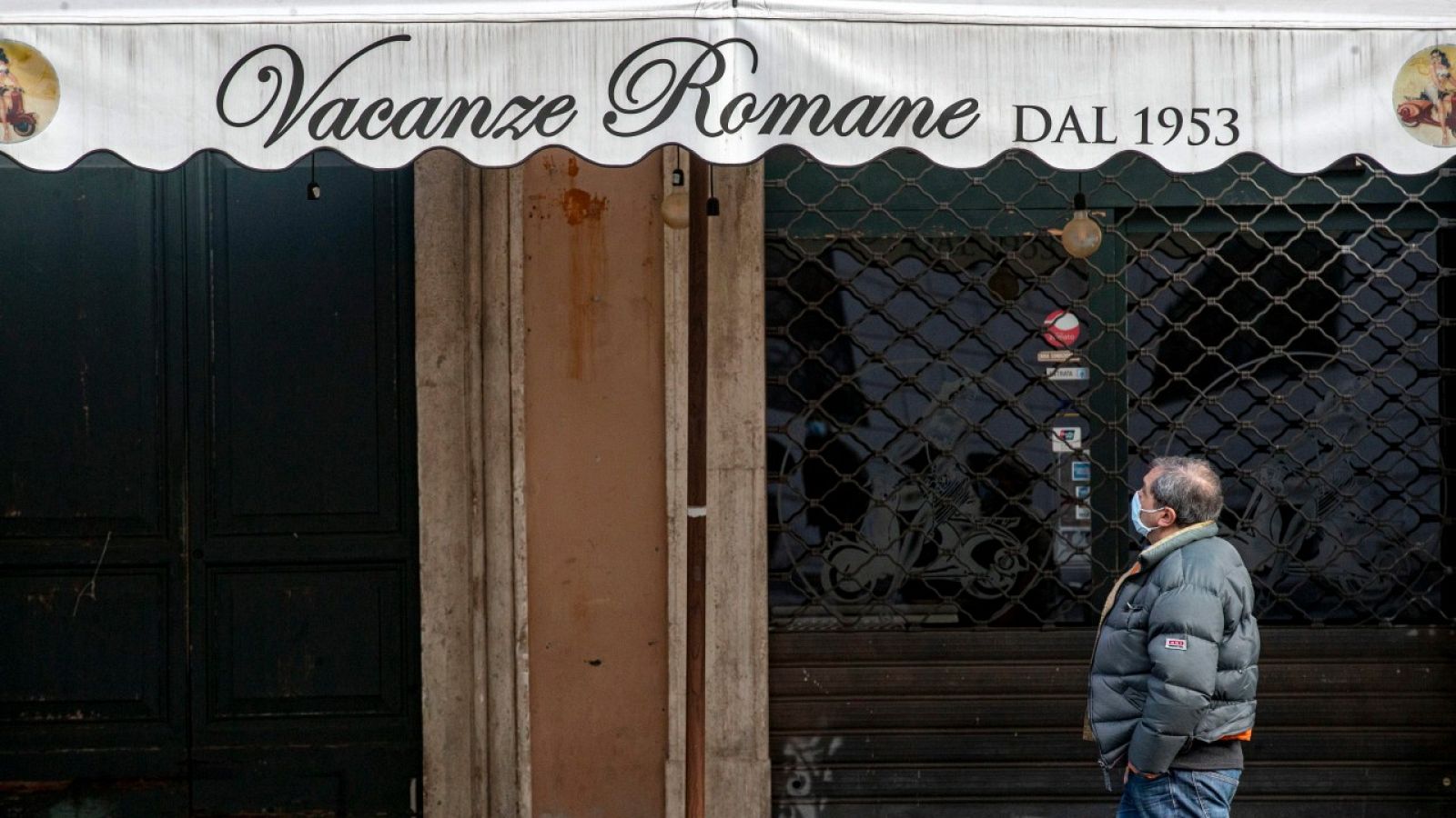 Un hombre con mascarilla caminando por la Plaza Navona en Roma, Italia.