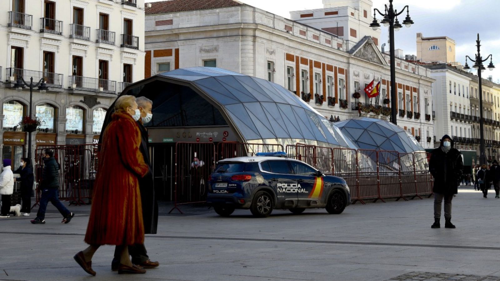 Dos personas con mascarilla pasean por la Puerta del Sol en Madrid