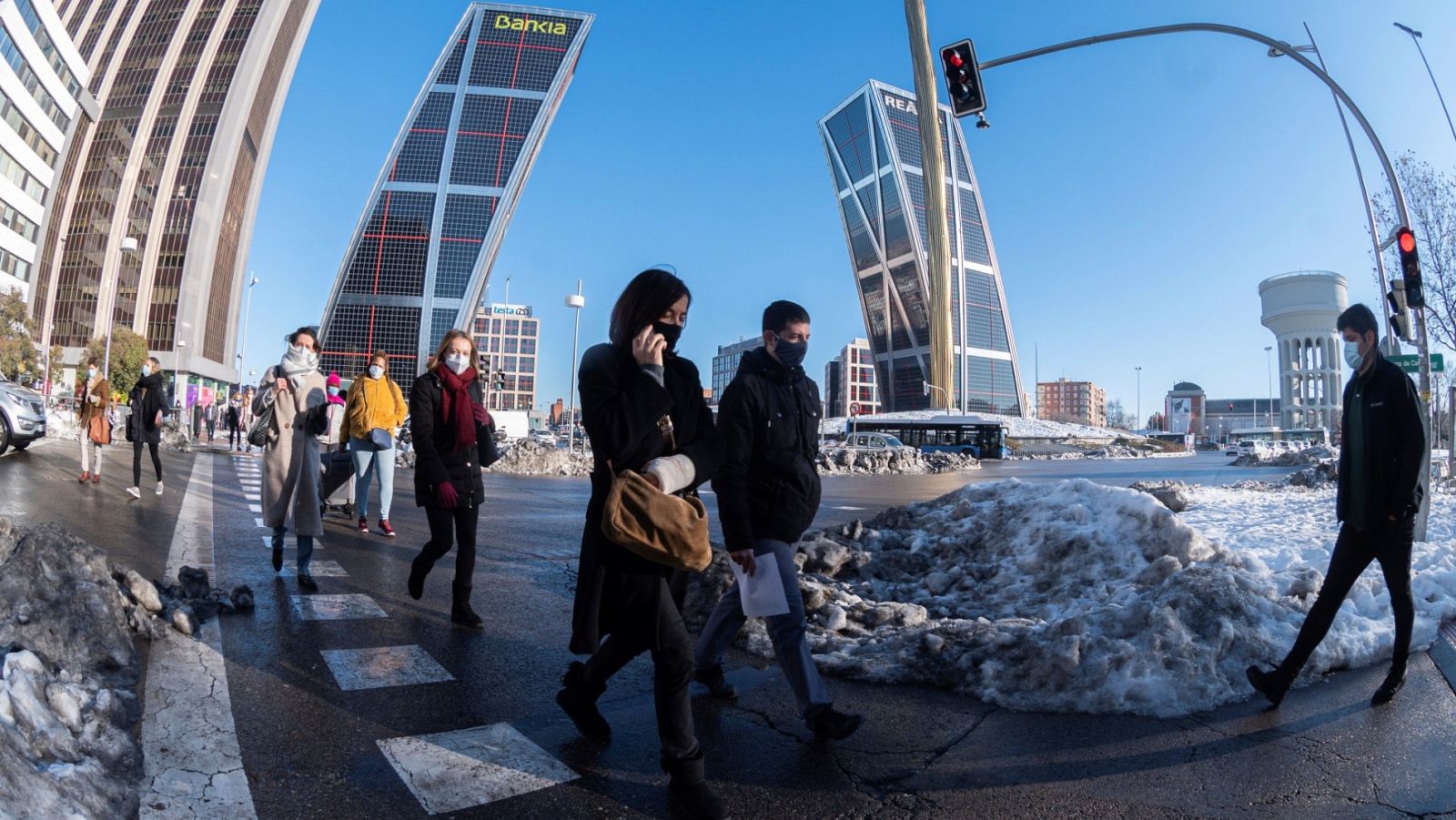 Peatones cruzan una calle en Plaza de Castilla en Madrid once días después de la nevada