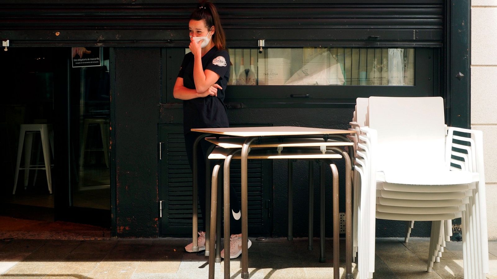 Una empleada junto a su local de trabajo cerrado por coronavirus