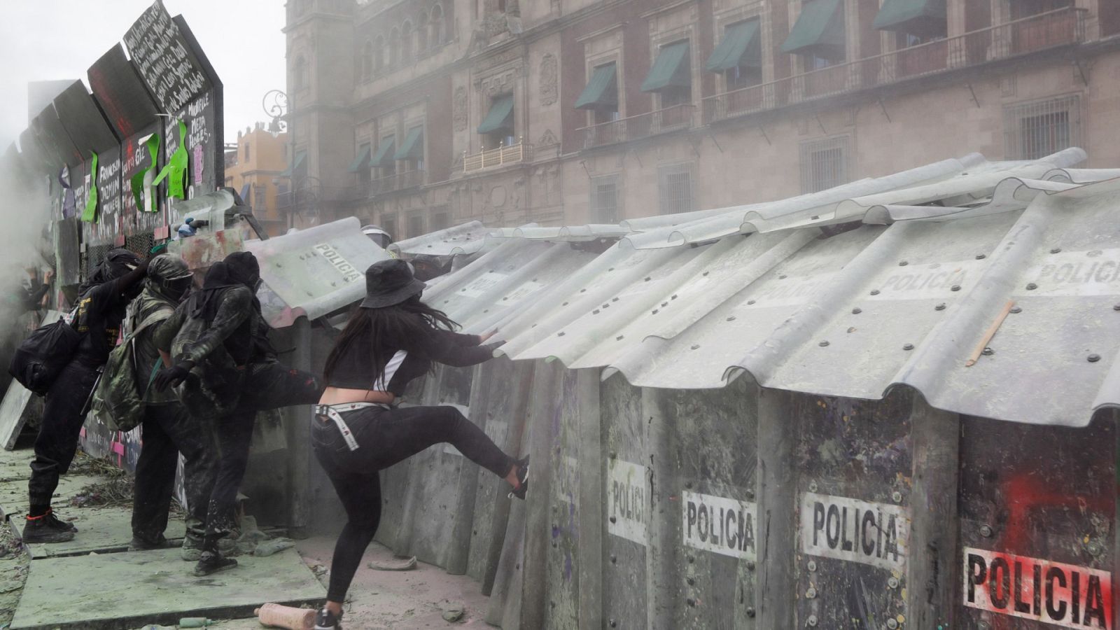 Mujeres patean los escudos de los agentes de policía durante una protesta frente al Palacio Nacional en el Día Internacional de la Mujer en la Ciudad de México, México