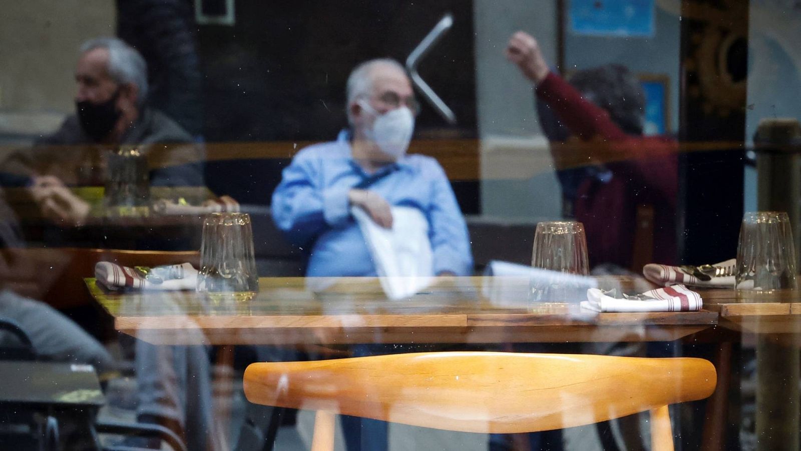 Varios hombres conversan junto a un restaurante vacío en San Sebastián