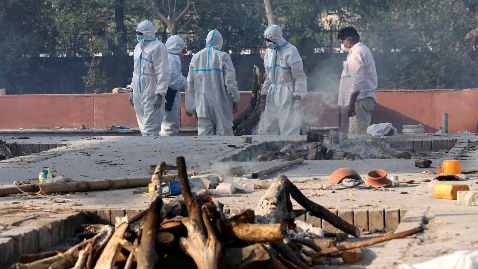 Los miembros de una familia, con equipo de protección personal (EPI), realizan los últimos ritos para las víctimas de COVID-19 en un crematorio cerca de Nueva Delhi, India.