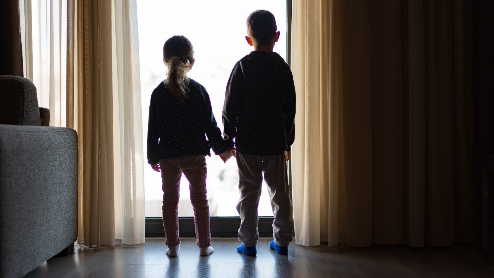 Una niña y un niño mirando por la ventana