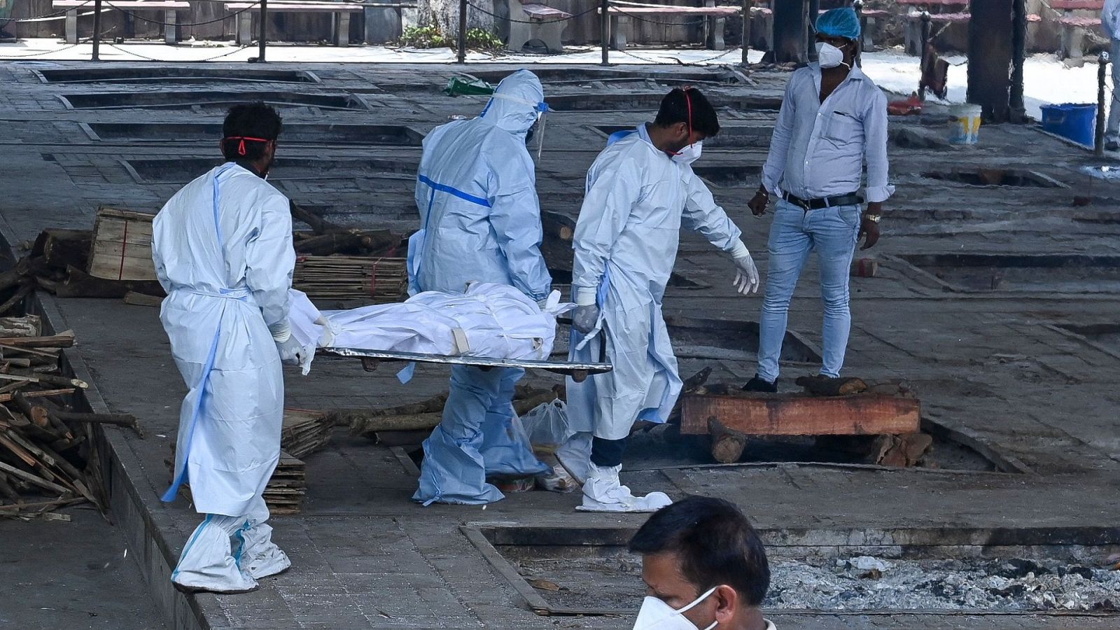 Personal sanitario traslada un cadáver de una persona fallecida por COVID-19 para su cremación, en Nueva Delhi (India)