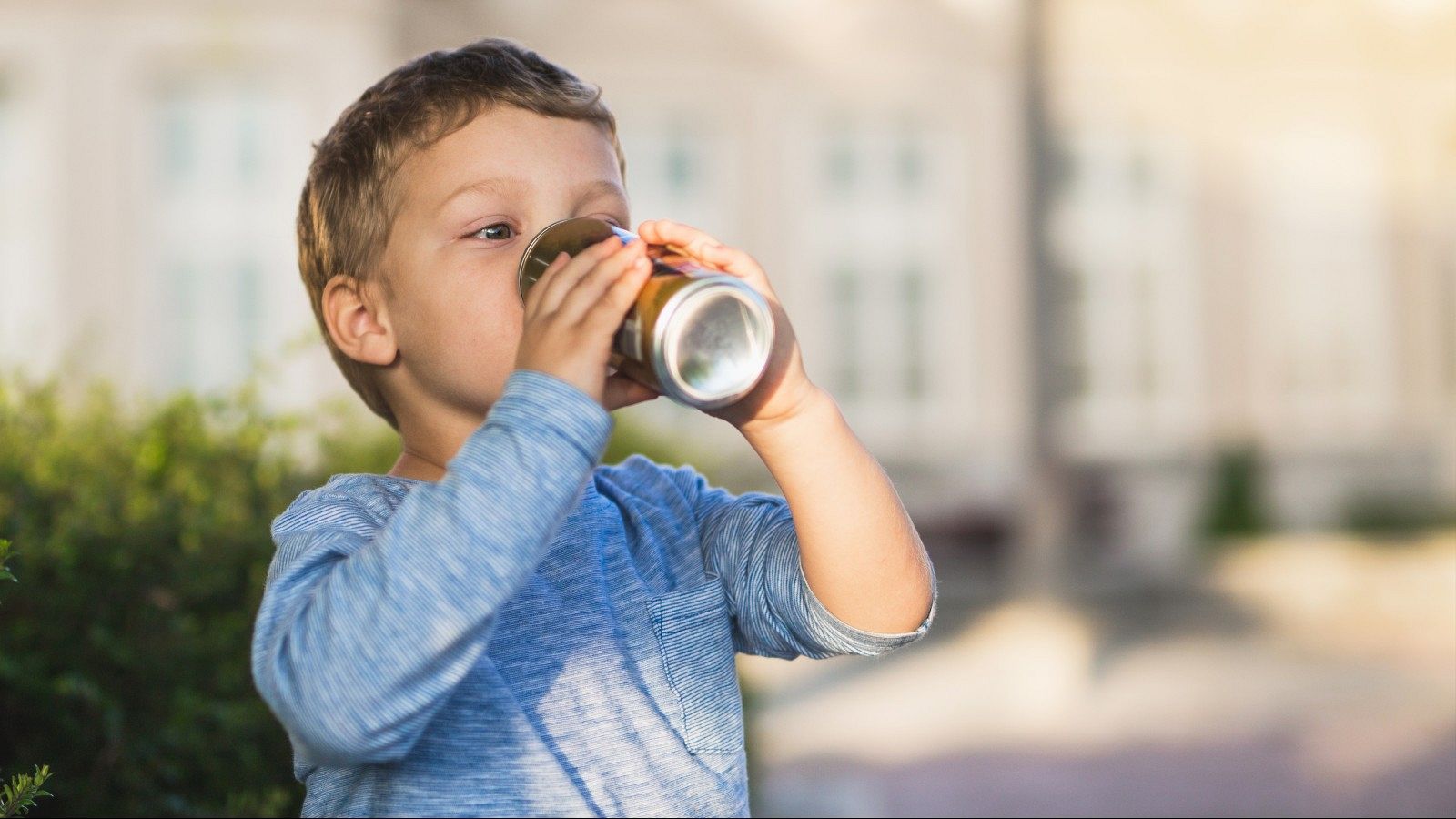 Un niño bebe de una lata de refresco