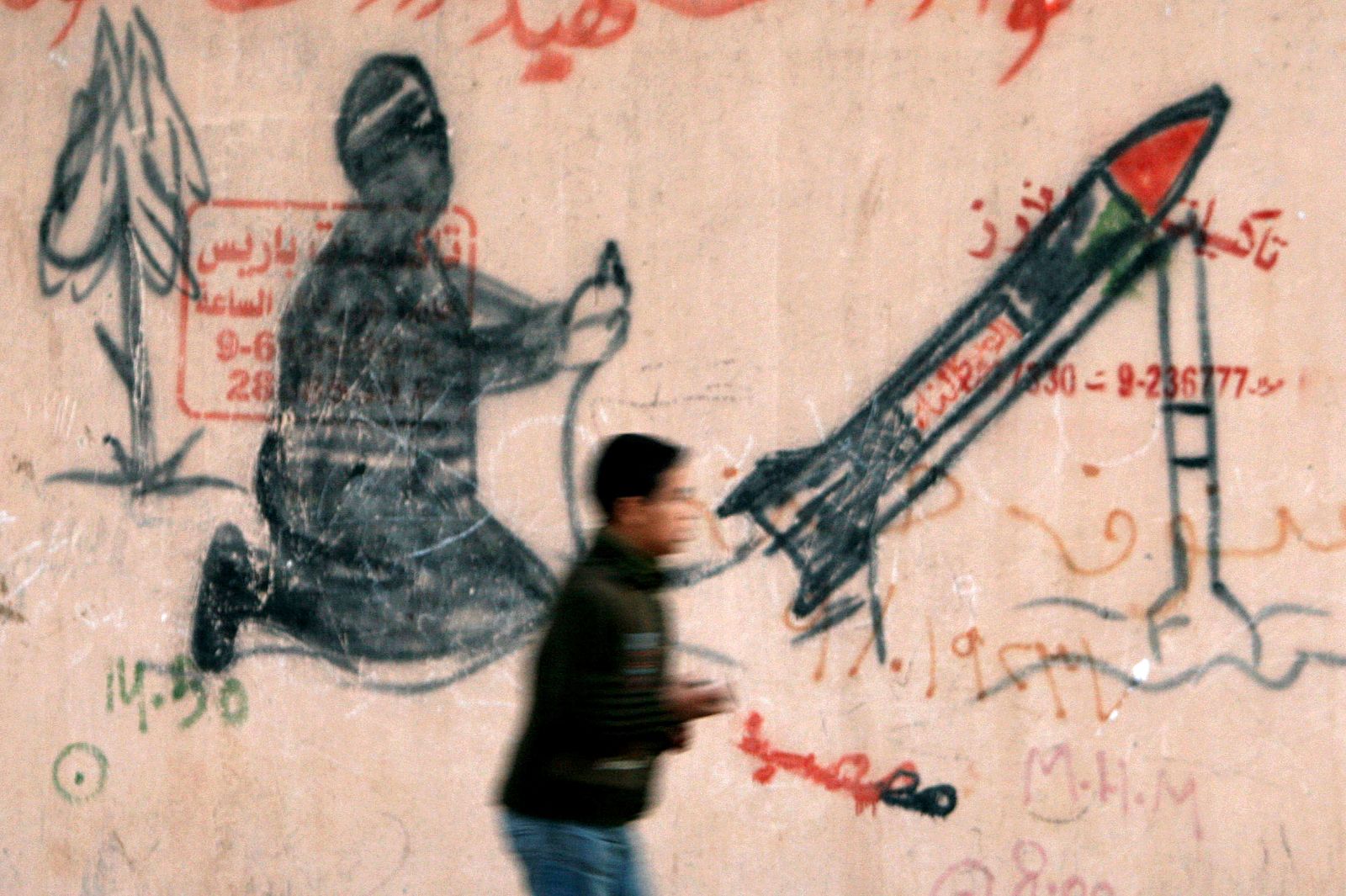 Un niño palestino camina frente a un mural de Gaza