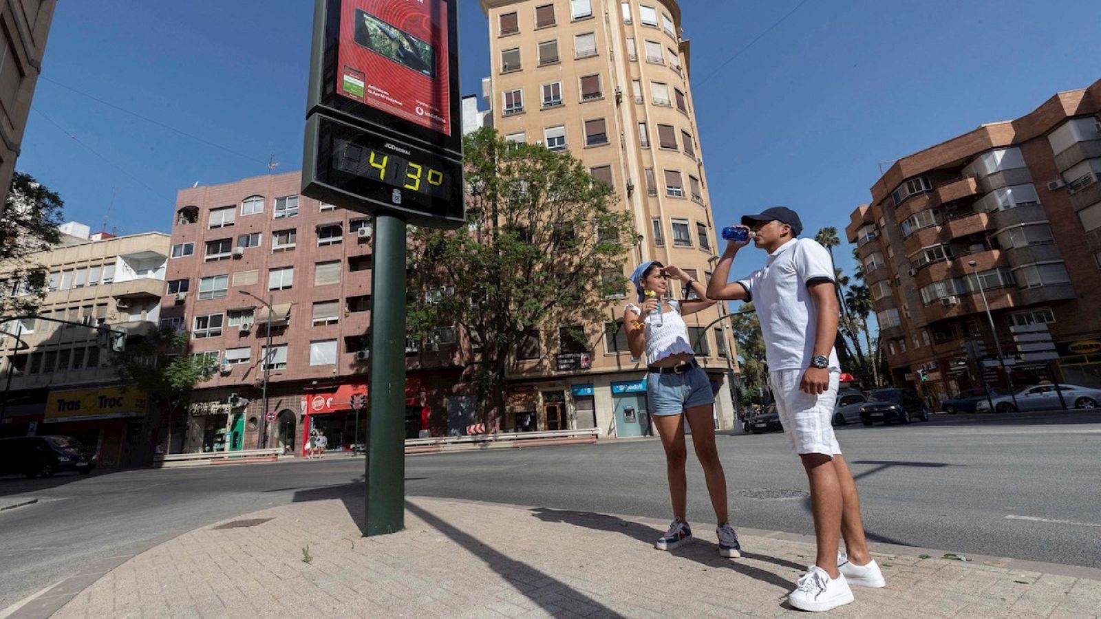 Jóvenes junto a un termómetro que marca 43 grados, en Murcia