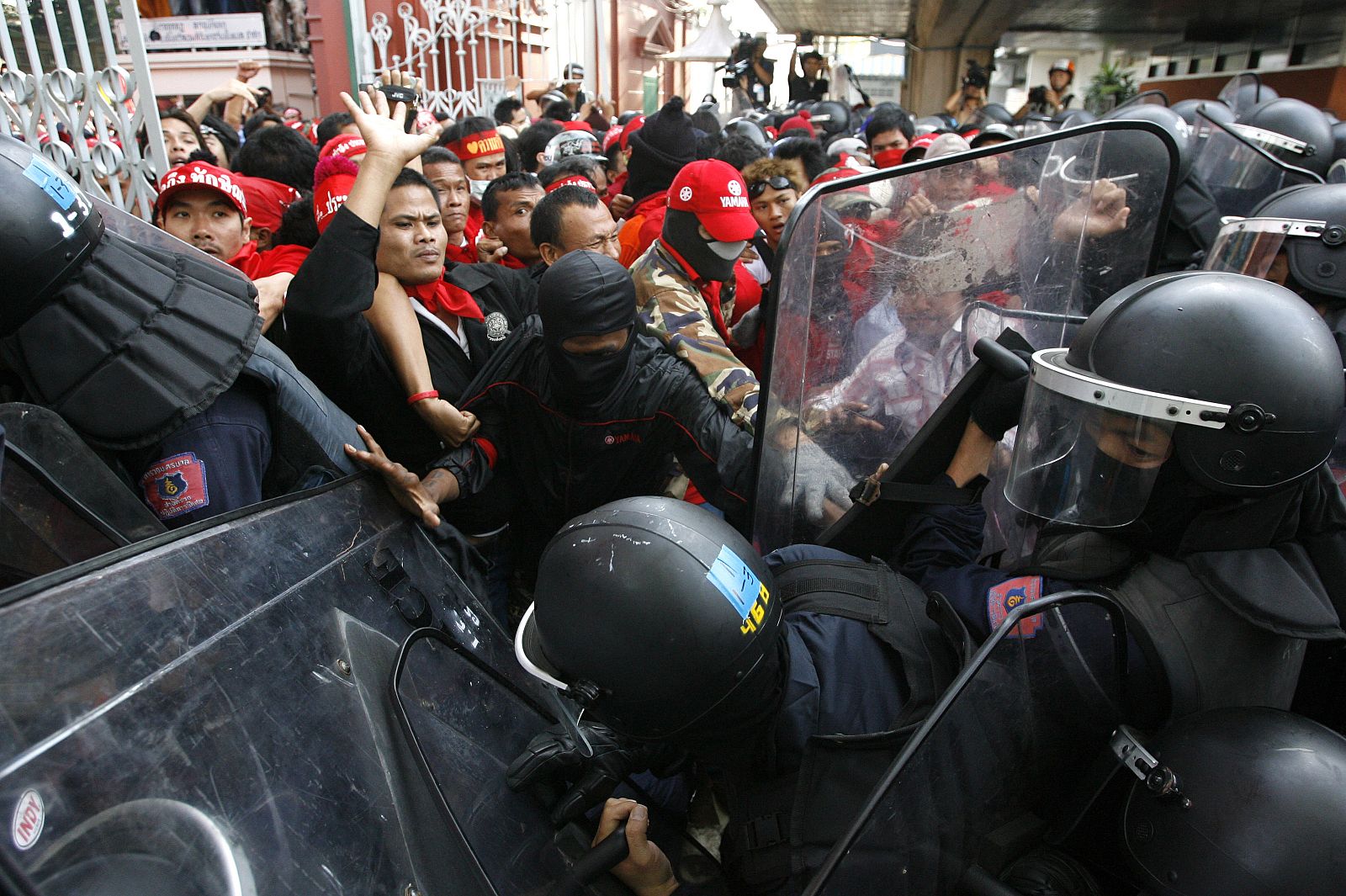 Supporters of former Prime Minister Thaksin Shinawatra confront riot police during a protest against the government outside Parliament in Bangkok
