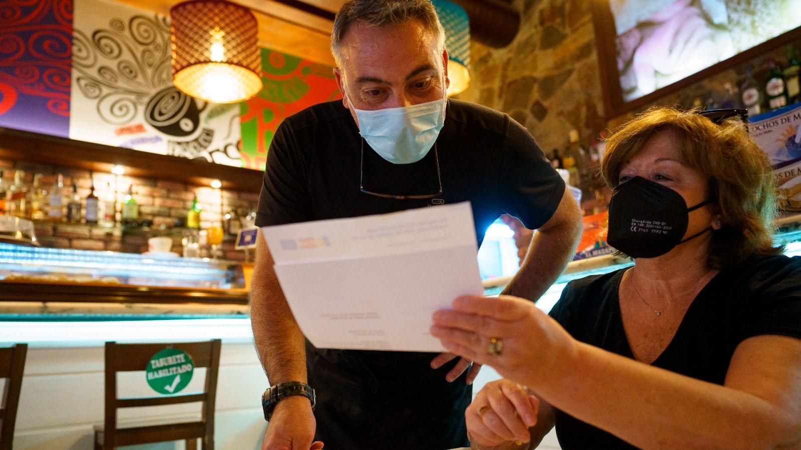 Personal de una cafetería de Santa Cruz de Tenerife, comprueba el certificado Covid de una clienta.