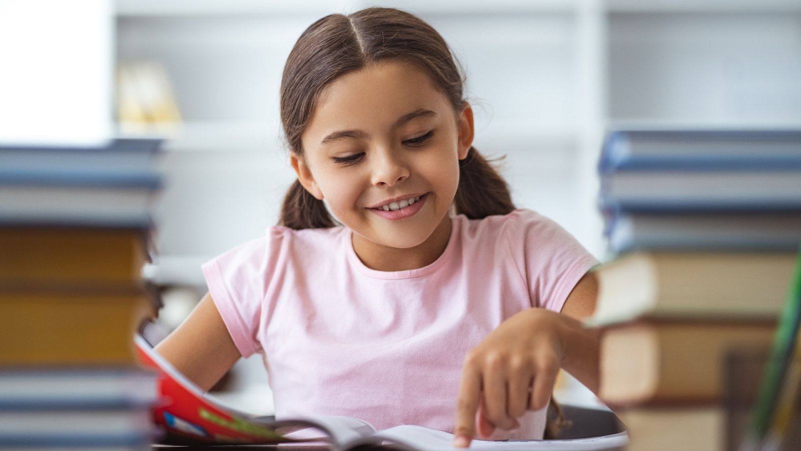 Una niña sonríe mientras lee un libro