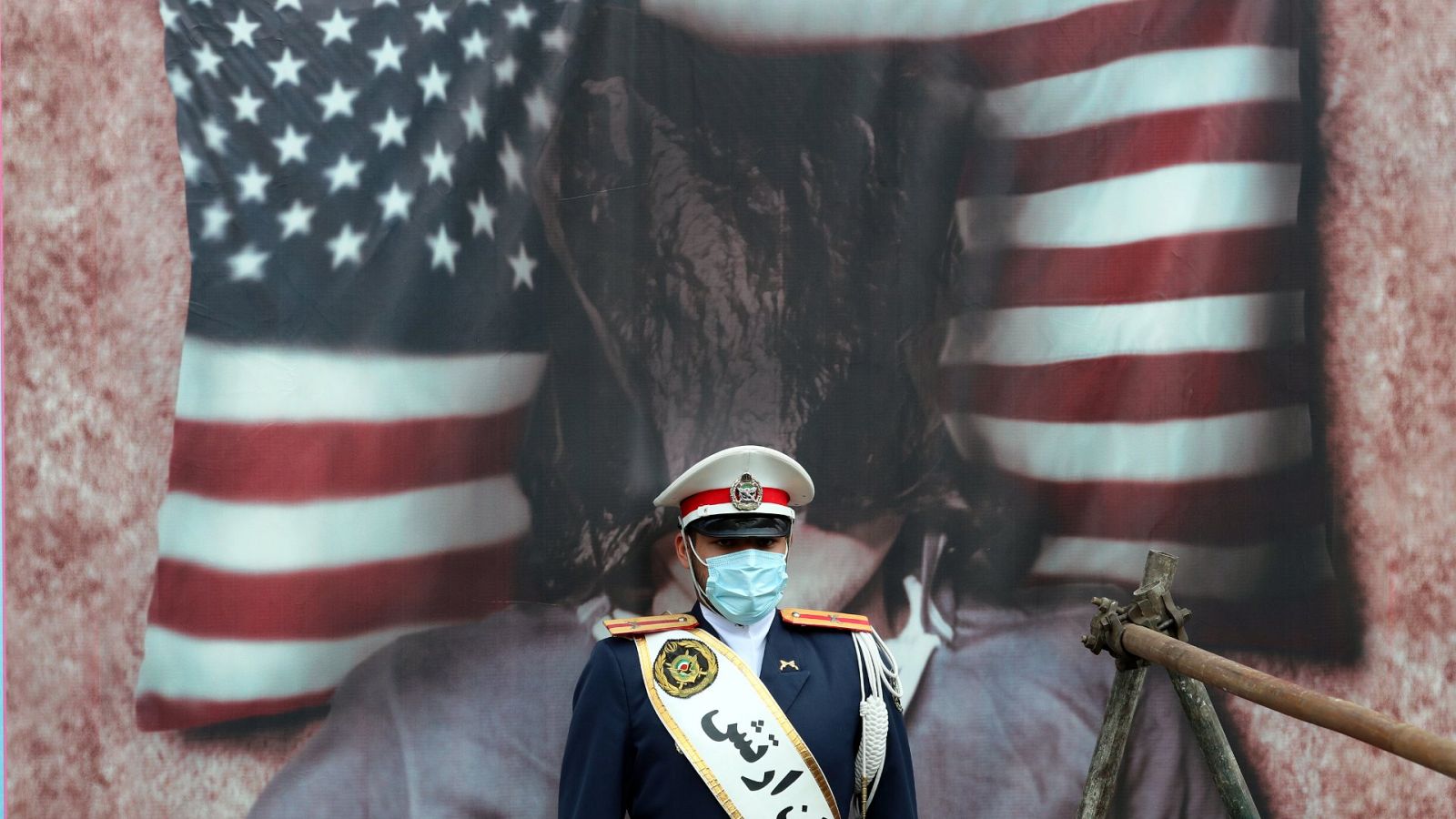 Un soldado iraní, delante de un cuadro de una bandera estadounidense quemada