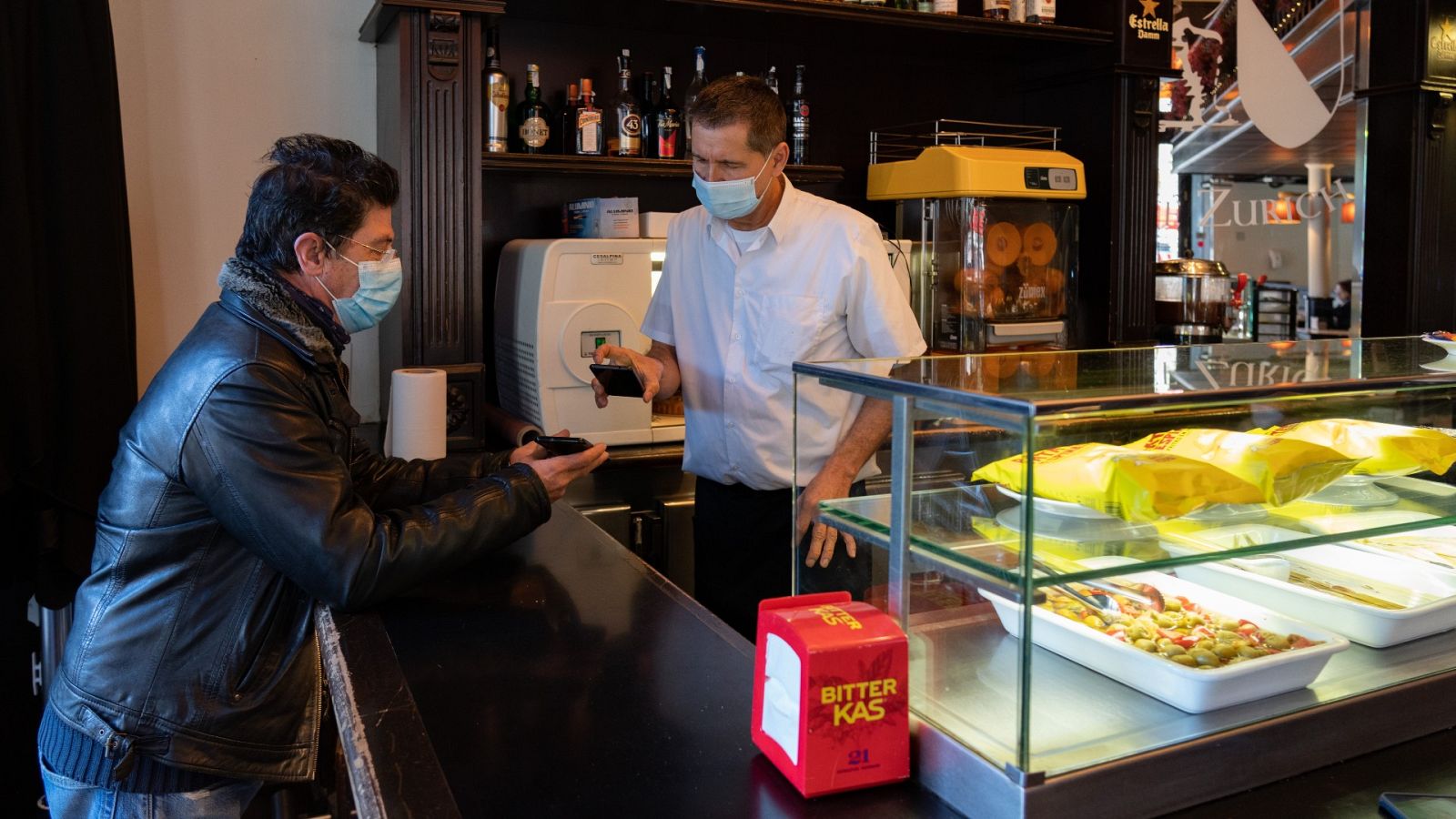 Un camarero escanea el código QR del certificado de vacunación de un cliente en Barcelona
