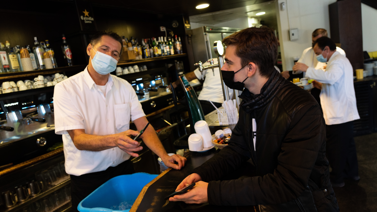 Un joven presenta el pasaporte COVID en una cafetería de Barcelona