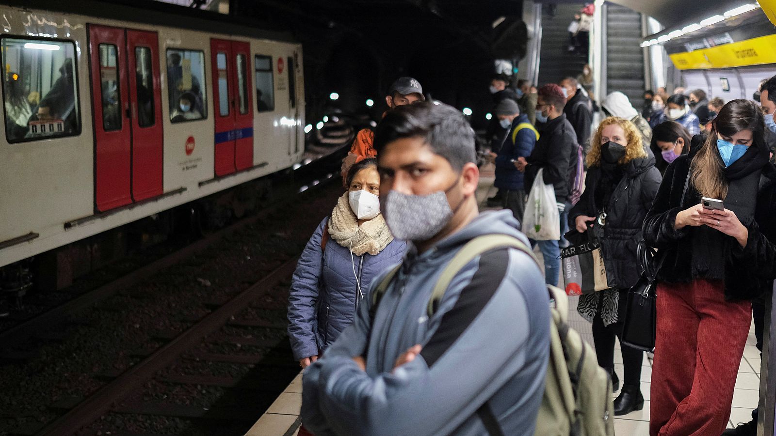 Varios pasajeros esperan en un andén del metro de Barcelona.