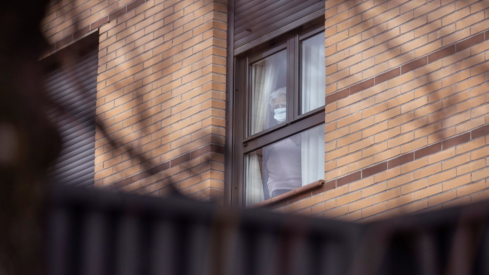Una mujer observa desde el interior de la residencia para mayores