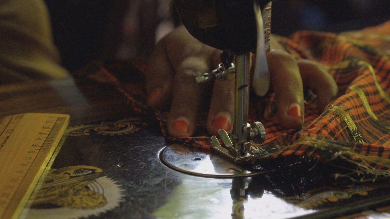 Manos de niña cosiendo a máquina