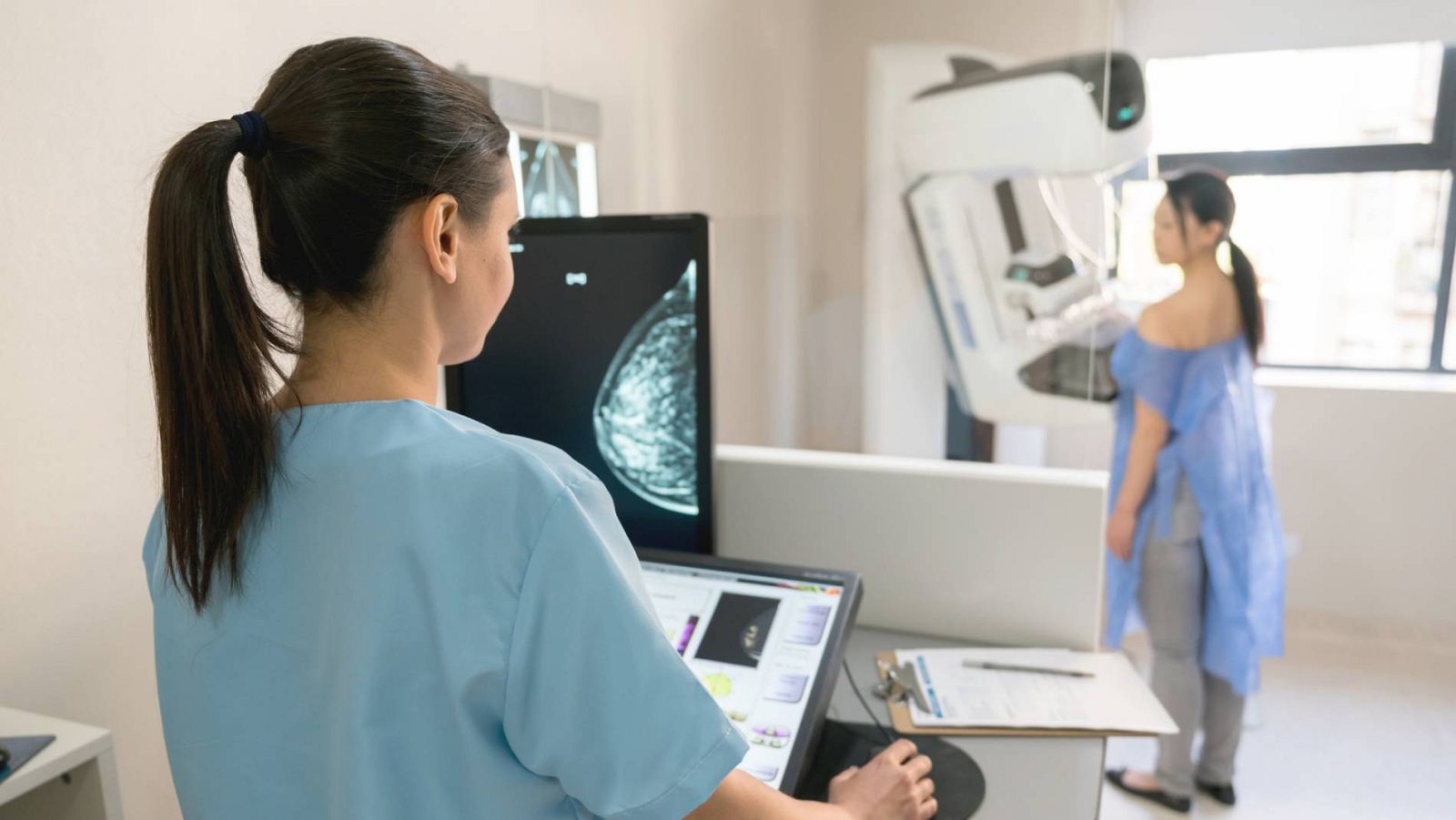 Una profesional sanitaria realiza una mamografía a una paciente