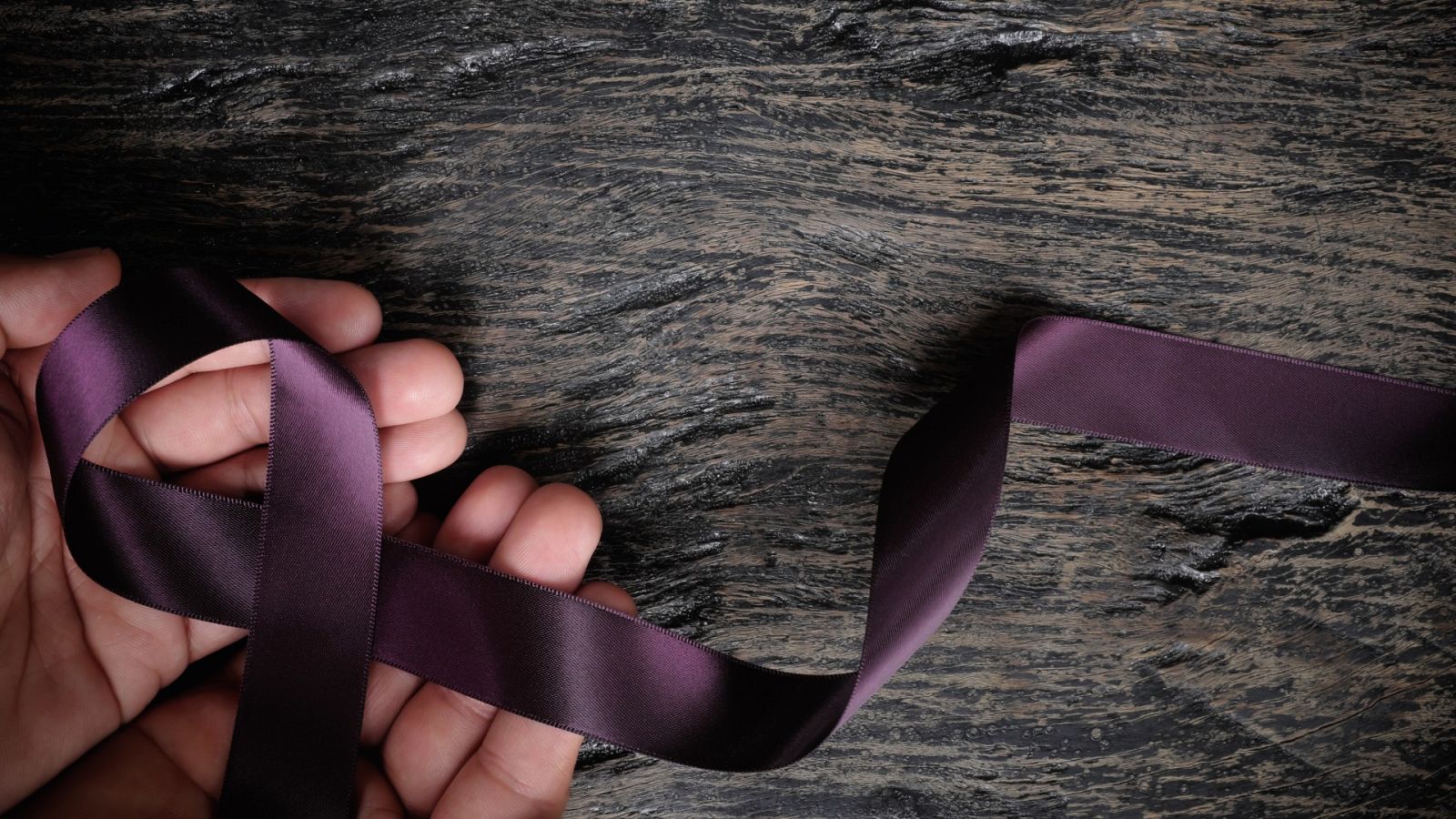 Una persona sostiene un lazo morado