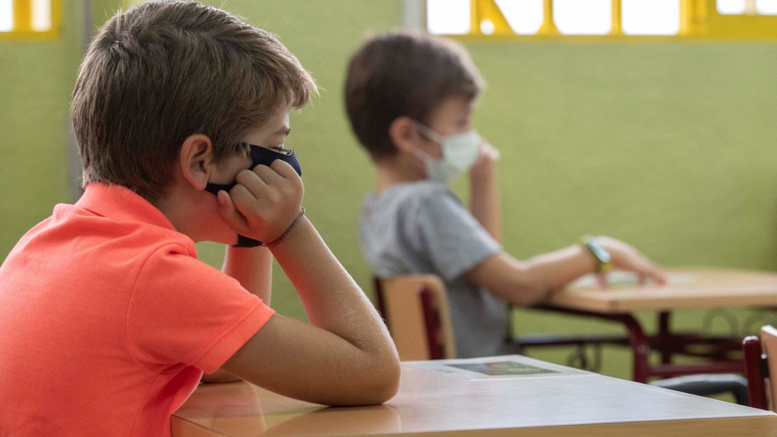 Dos niños atienden en clase con las mascarillas puestas