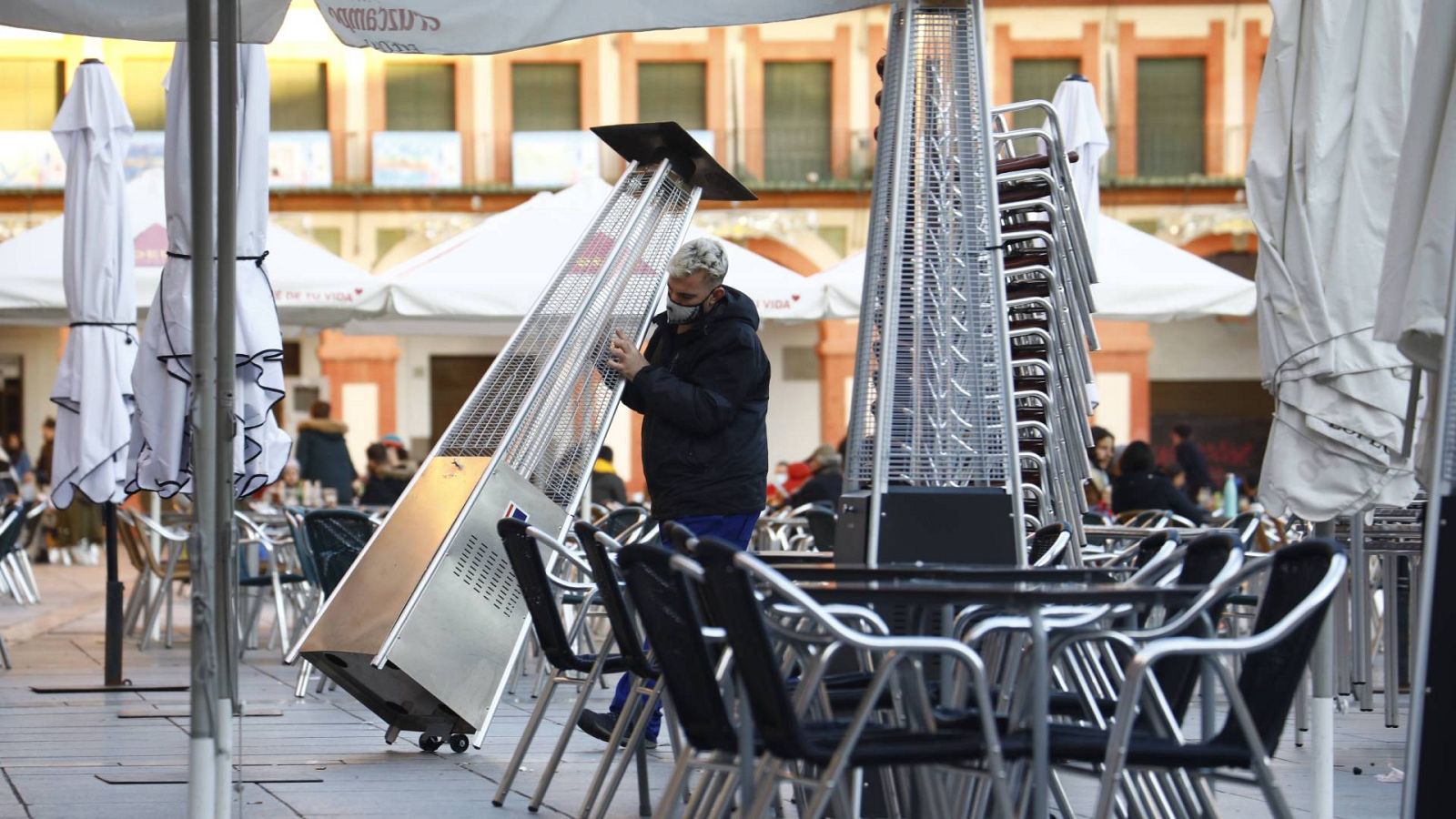 Un trabajador recoge el mobiliario de la terraza de un restaurante en el centro de Córdoba
