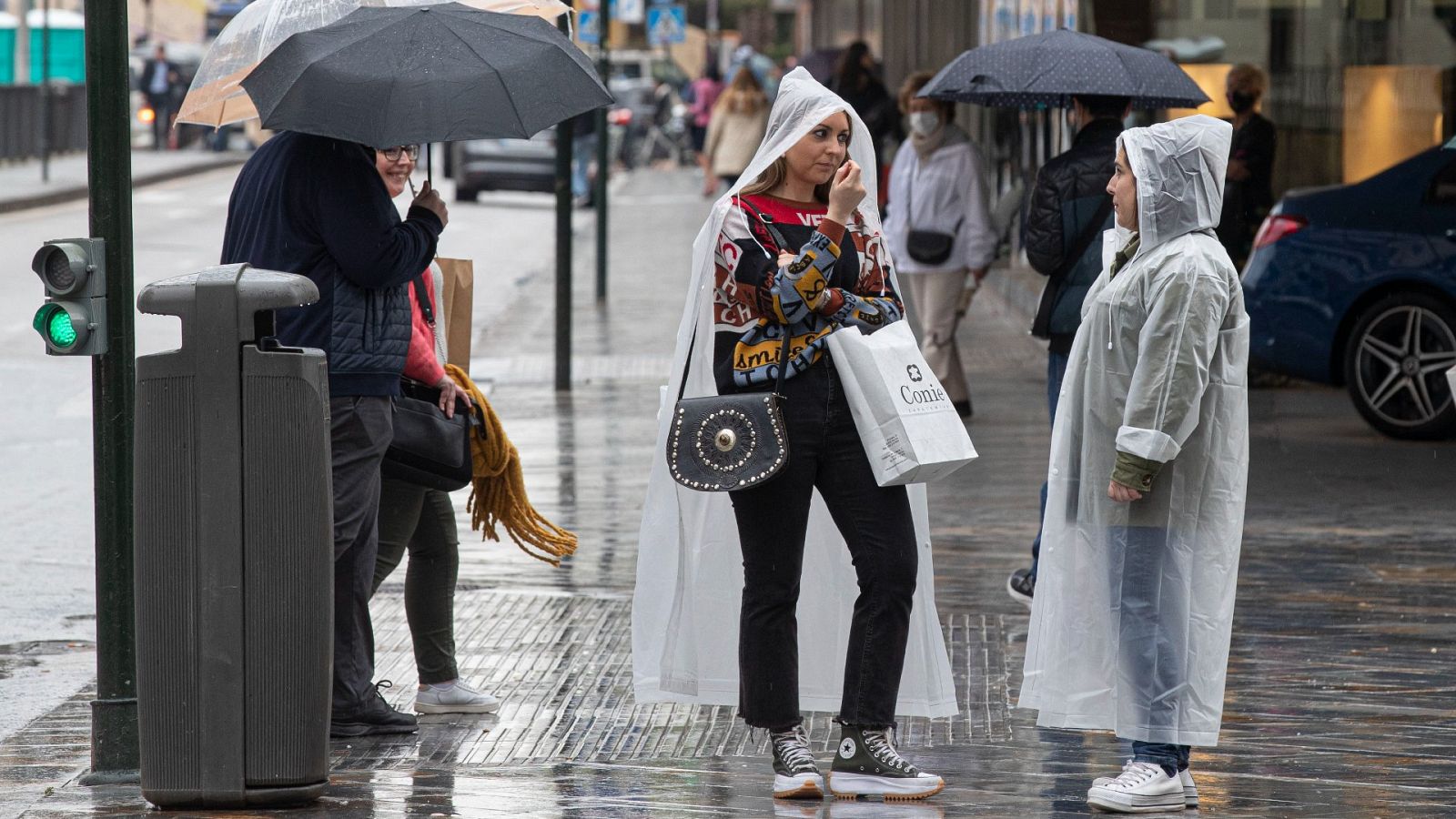 Varias personas se protegen de la lluvia en la Gran Vía de Murcia
