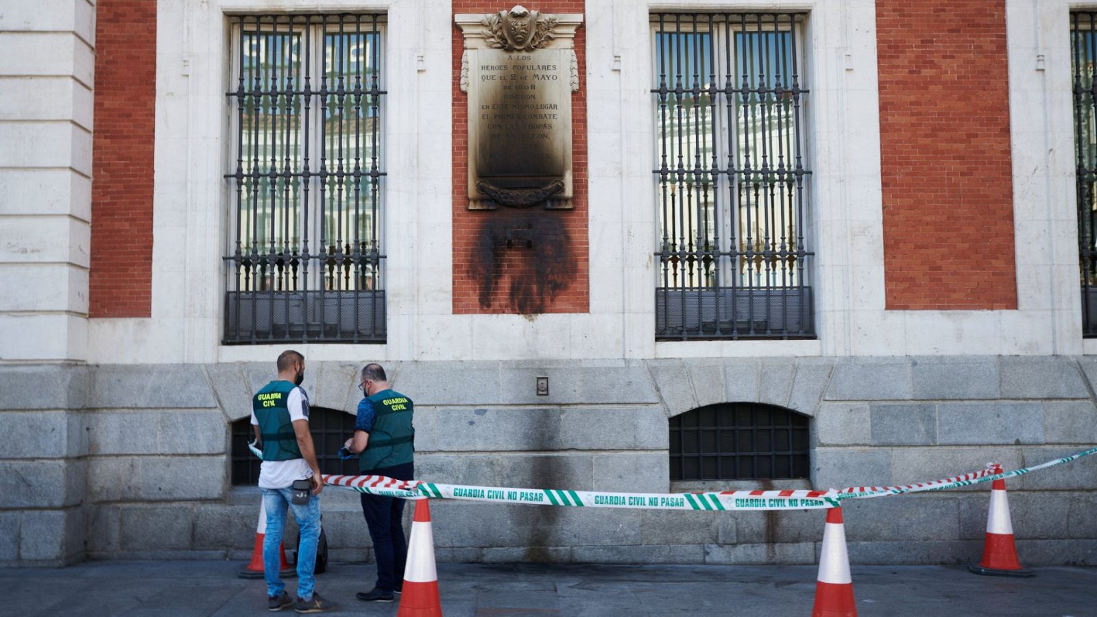 Dos guardias civiles conversan junto a la placa quemada de los Héroes del 2 de mayo