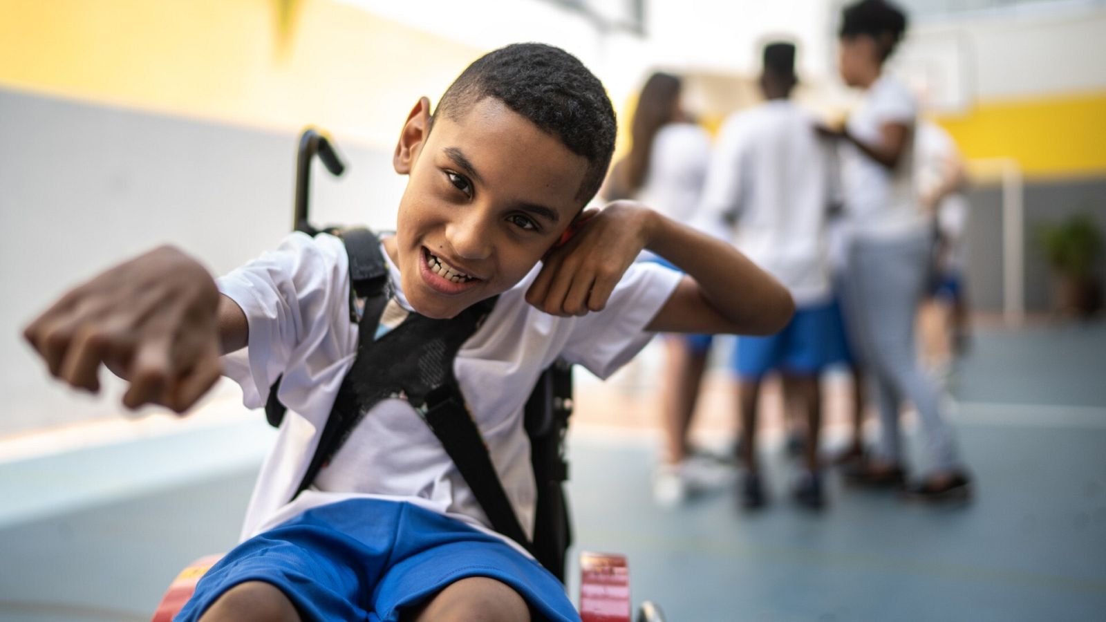 Un niño en silla de ruedas juega en el patio de un colegio