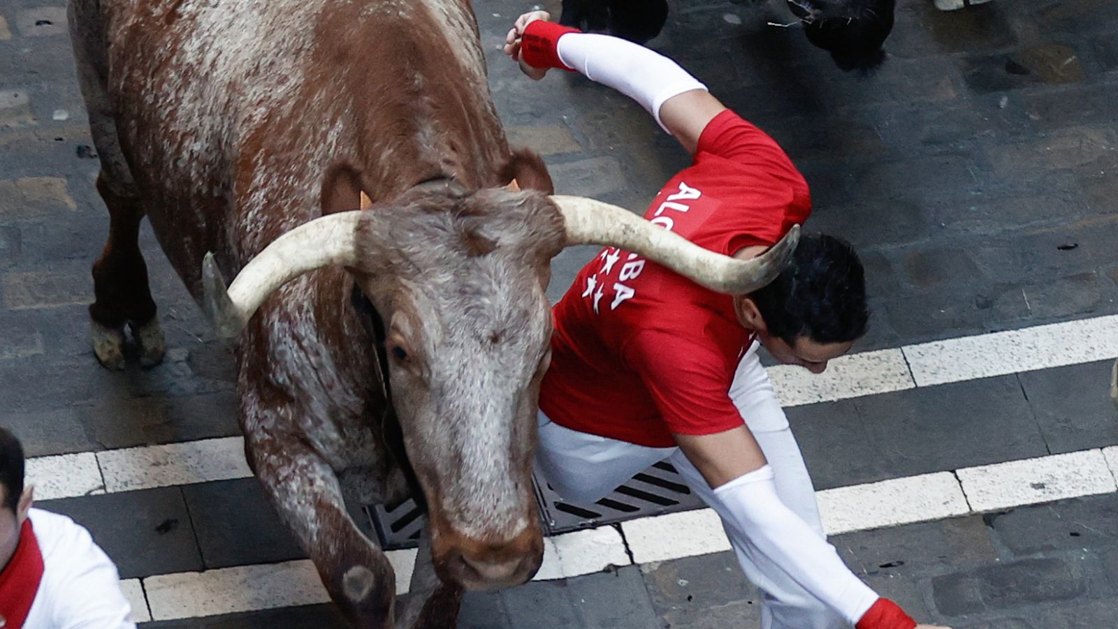Un mozo pasa rozando a un astado durante el séptimo encierro de los Sanfermines ante los toros de la ganadería de Victoriano del Río.
