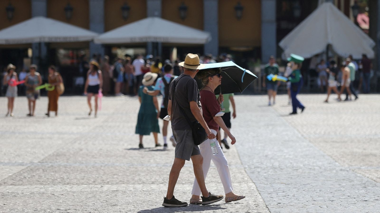 Una pareja se refugia del sol bajo una sombrilla en la Plaza Mayor, Madrid