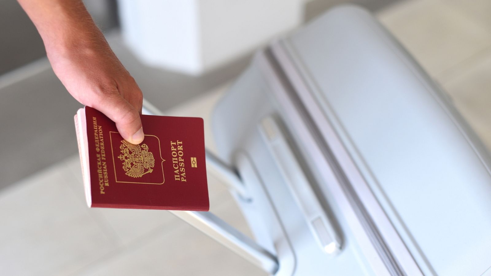 Un hombre sostiene un pasaporte ruso y una maleta