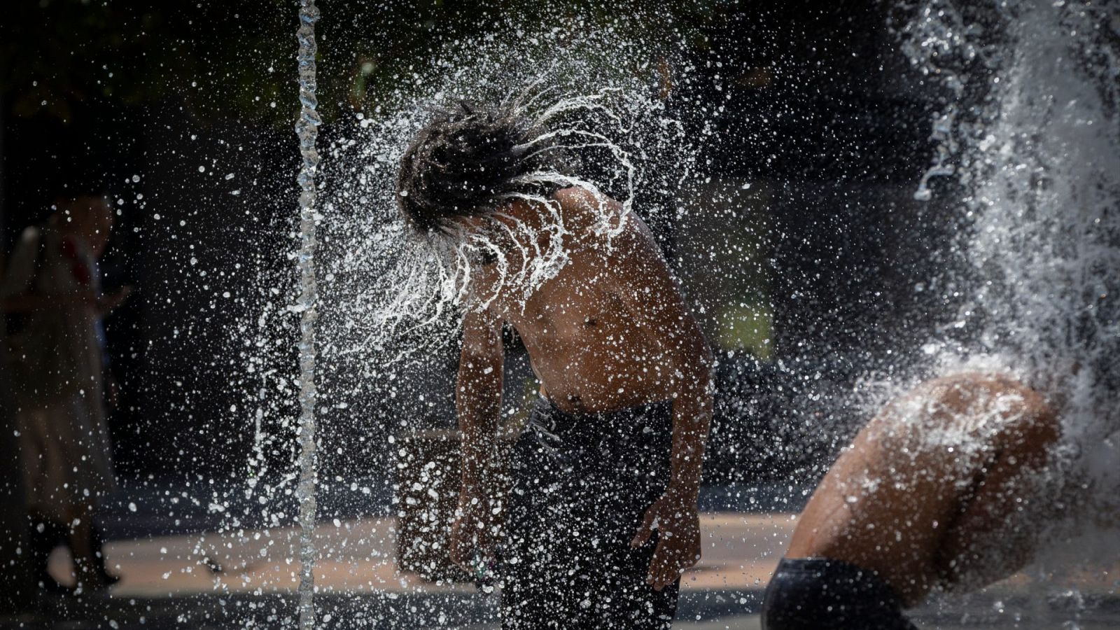 Un hombre se refresca en una fuente de Pamplona
