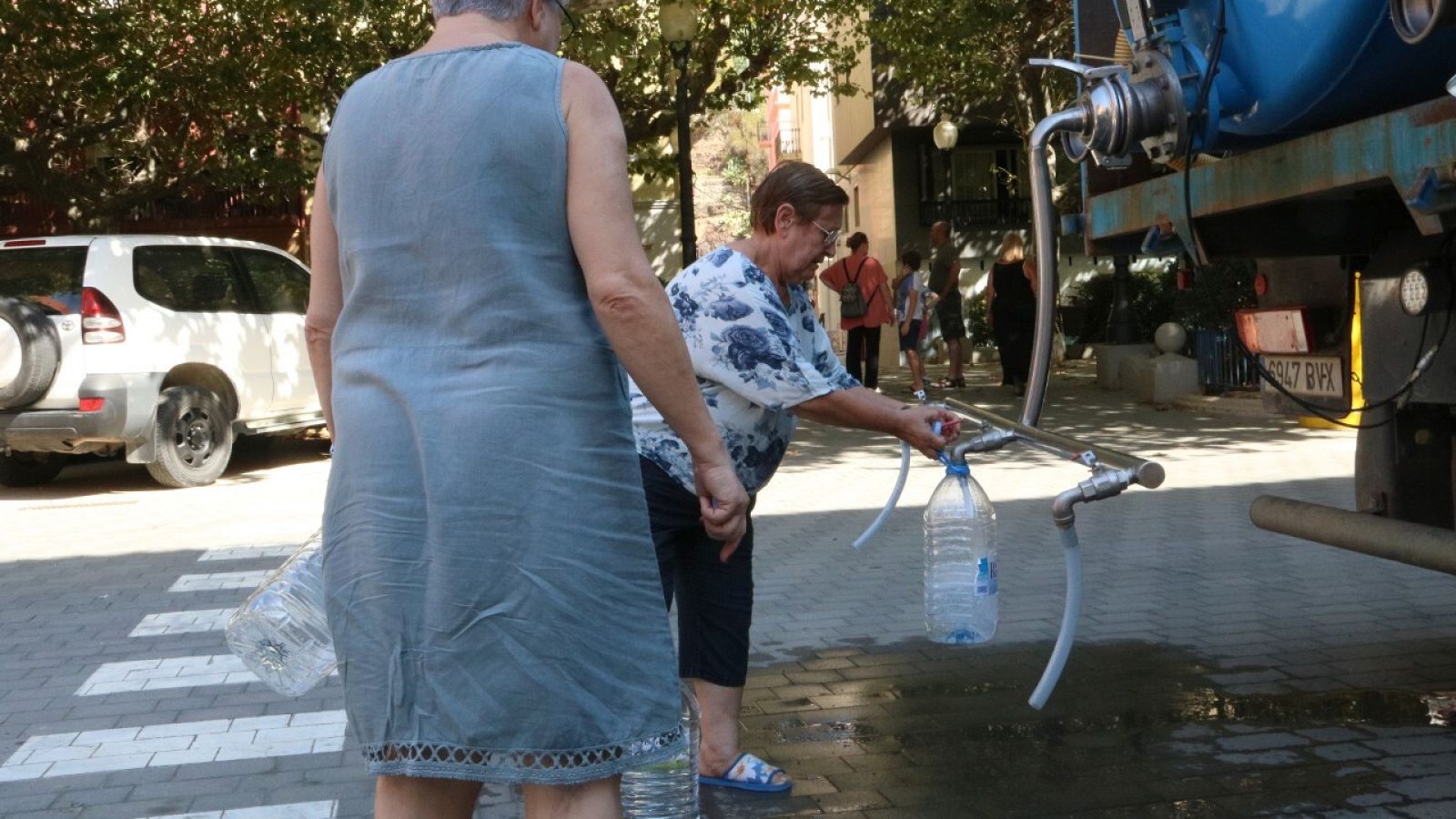 Dues dones omplint garrafes d'aigua del camió cisterna a Portbou