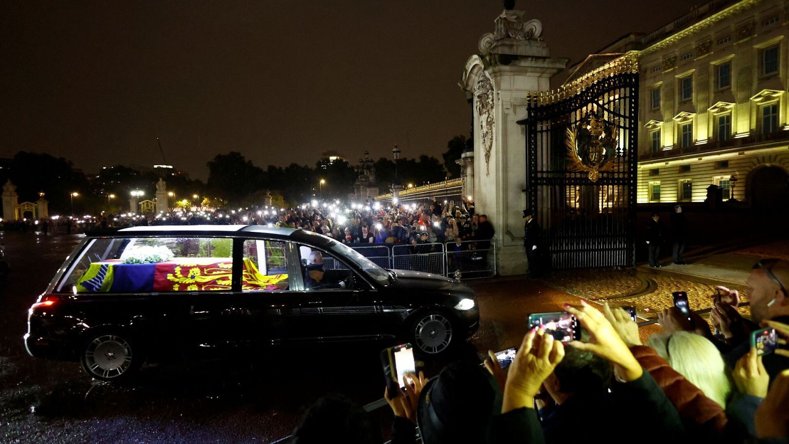 La gente observa el coche fúnebre que lleva el féretro de la reina Isabel II de Inglaterra frente al Palacio de Buckingham