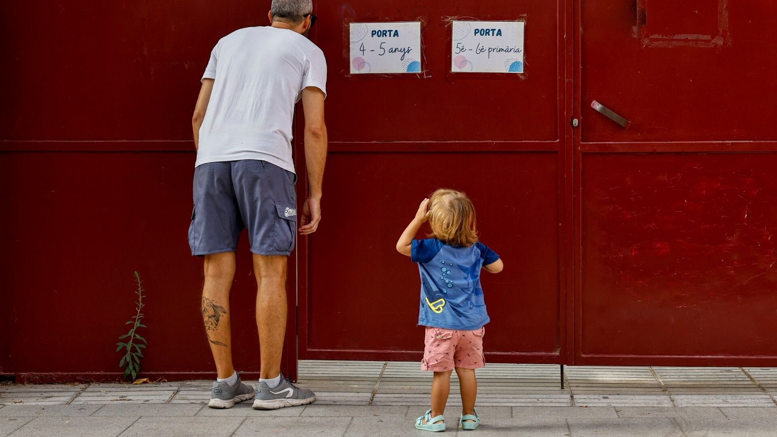 Un padre y su hija aguardan para entrar durante el primer día de colegio