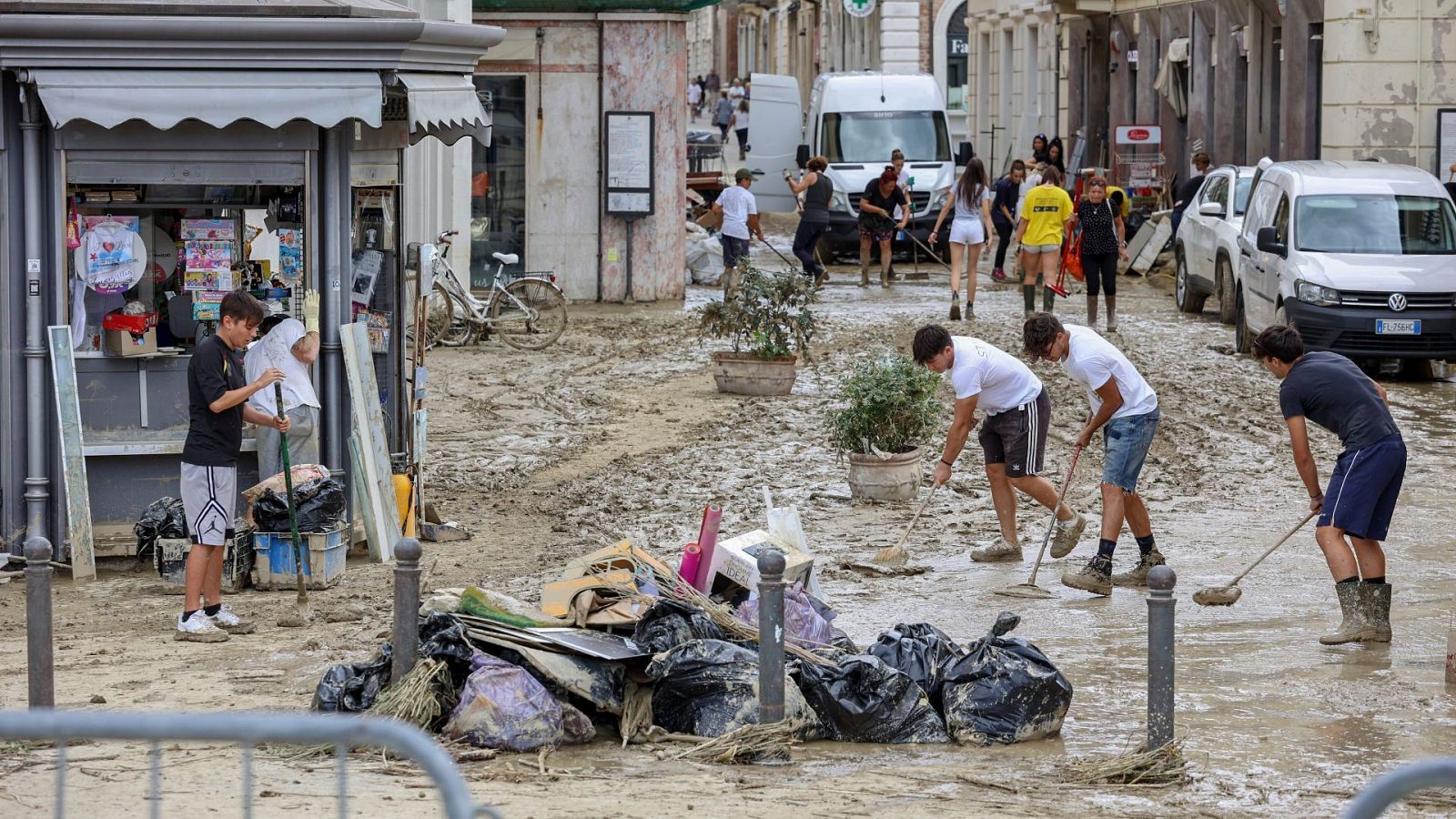 La gente quita el lodo de una calle en Senigallia, Italia central