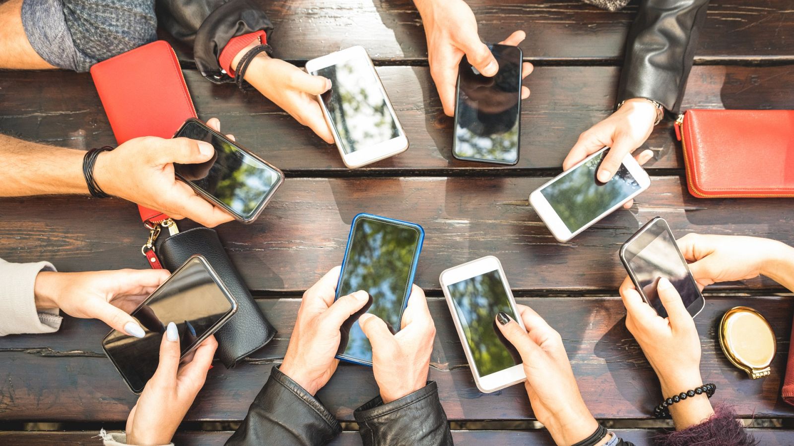 Un grupo de jóvenes usa sus teléfonos móviles