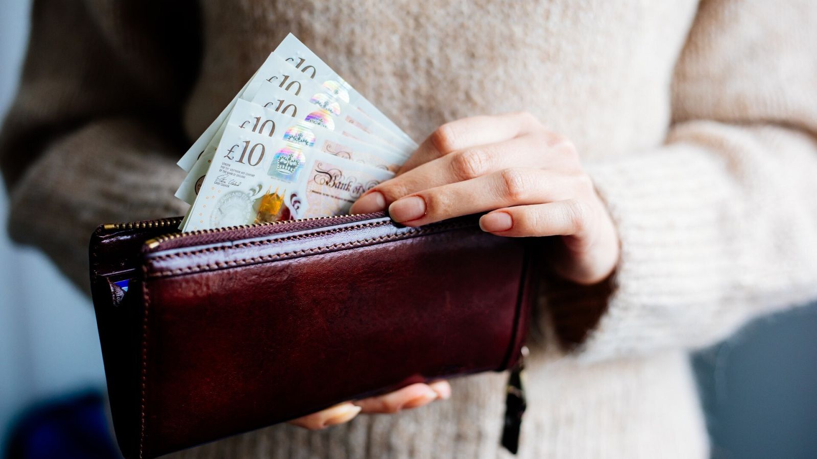 Una persona saca libras esterlinas de su cartera